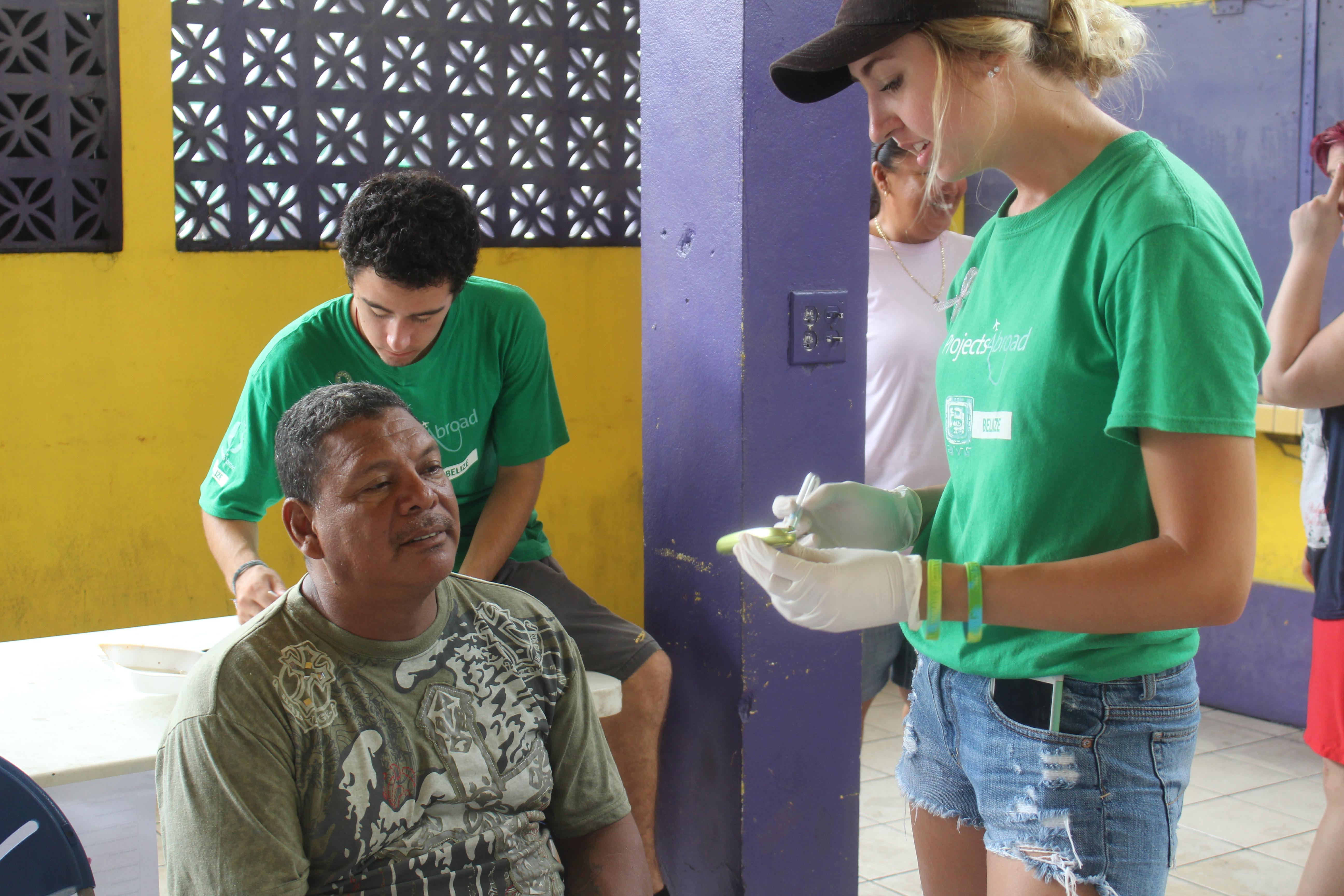 At a Public Health placement for teenagers in Belize, a student assists a local man. On the Projects Abroad Public Health internship for teenagers in Belize, a student and local man talk.